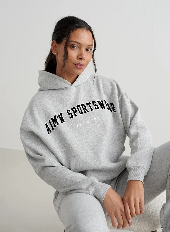 Women's pullover hoodie with a side slit for a modern and relaxed fitGrey Melange Varsity Sweat Hood Women's pullover hoodie with a side slit for a modern and relaxed fitGrey Melange Varsity Sweat Hood